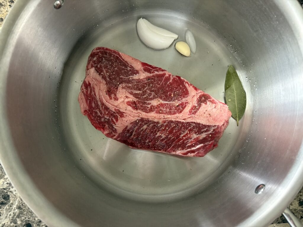 Top view of beef barbacoa ingredients in a pot before cooking.