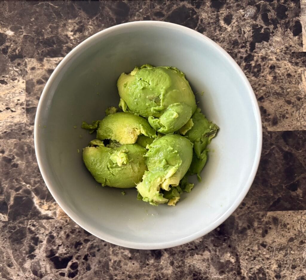 Top view of avocado flesh in a bowl.
