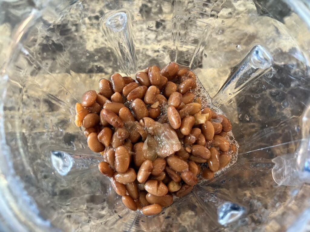 Top view of cooked beans and their cooking liquid in a blender.