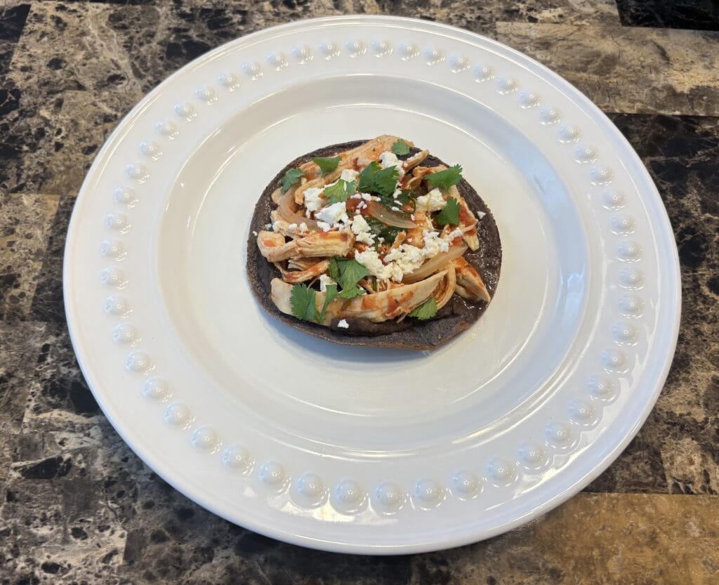 Chicken tinga tostada on a white plate.