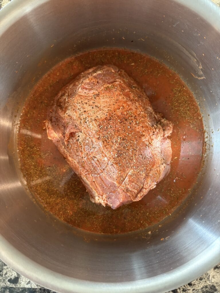 Top view of pork meat and marinade for cochinita pibil in a pot before cooking.