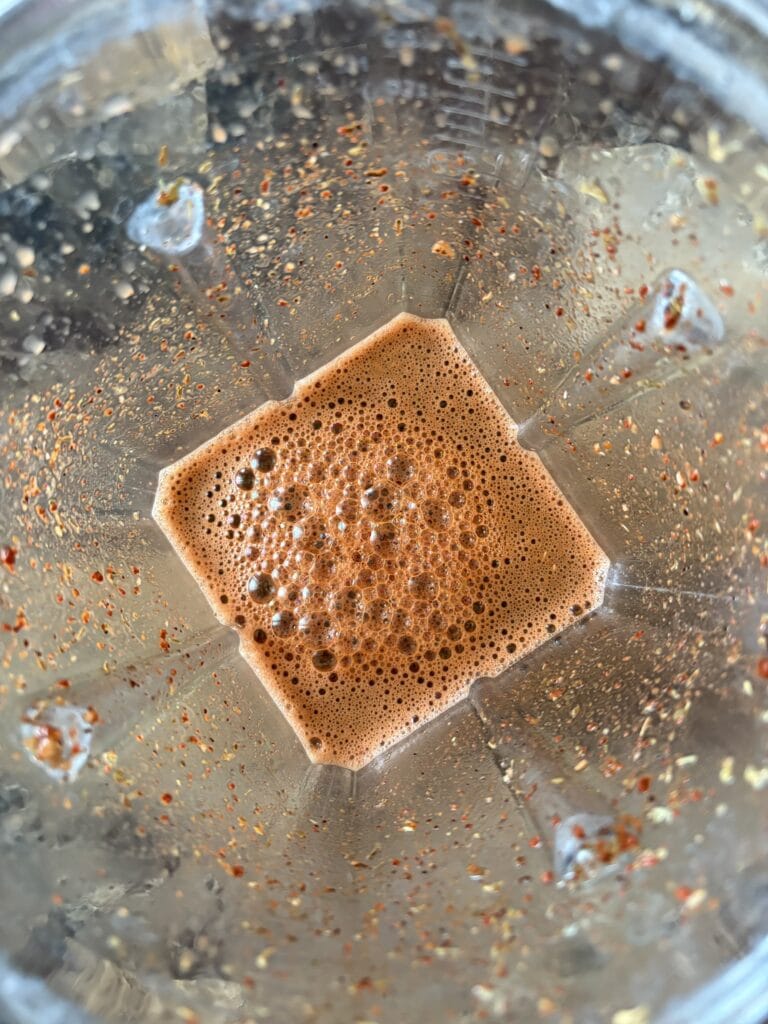 Top view of blended ingredients and spices for cochinita pibil in a blender.
