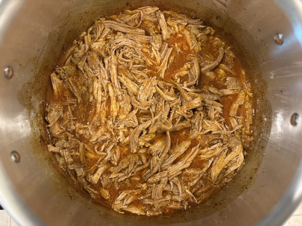 Top view of cooked cochinita pibil meat shredded in a pot.