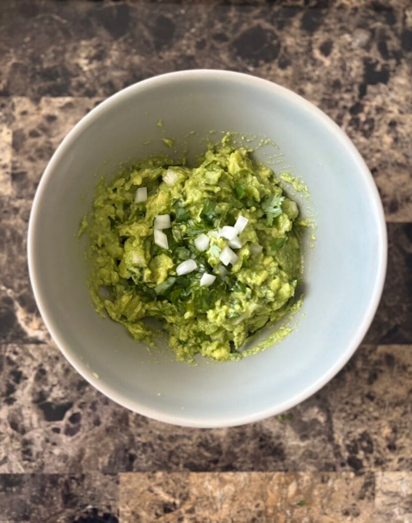 Top view of guacamole garnished with cilantro and onion in a bowl