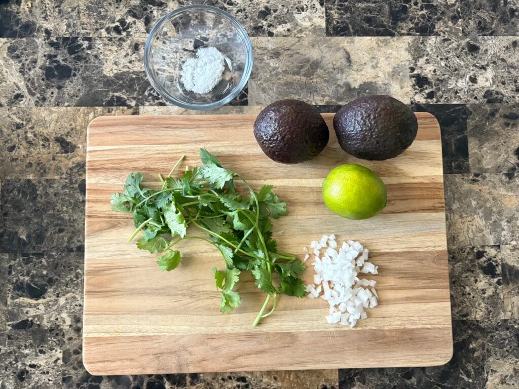 Top view of guacamole ingredients on a cutting board.