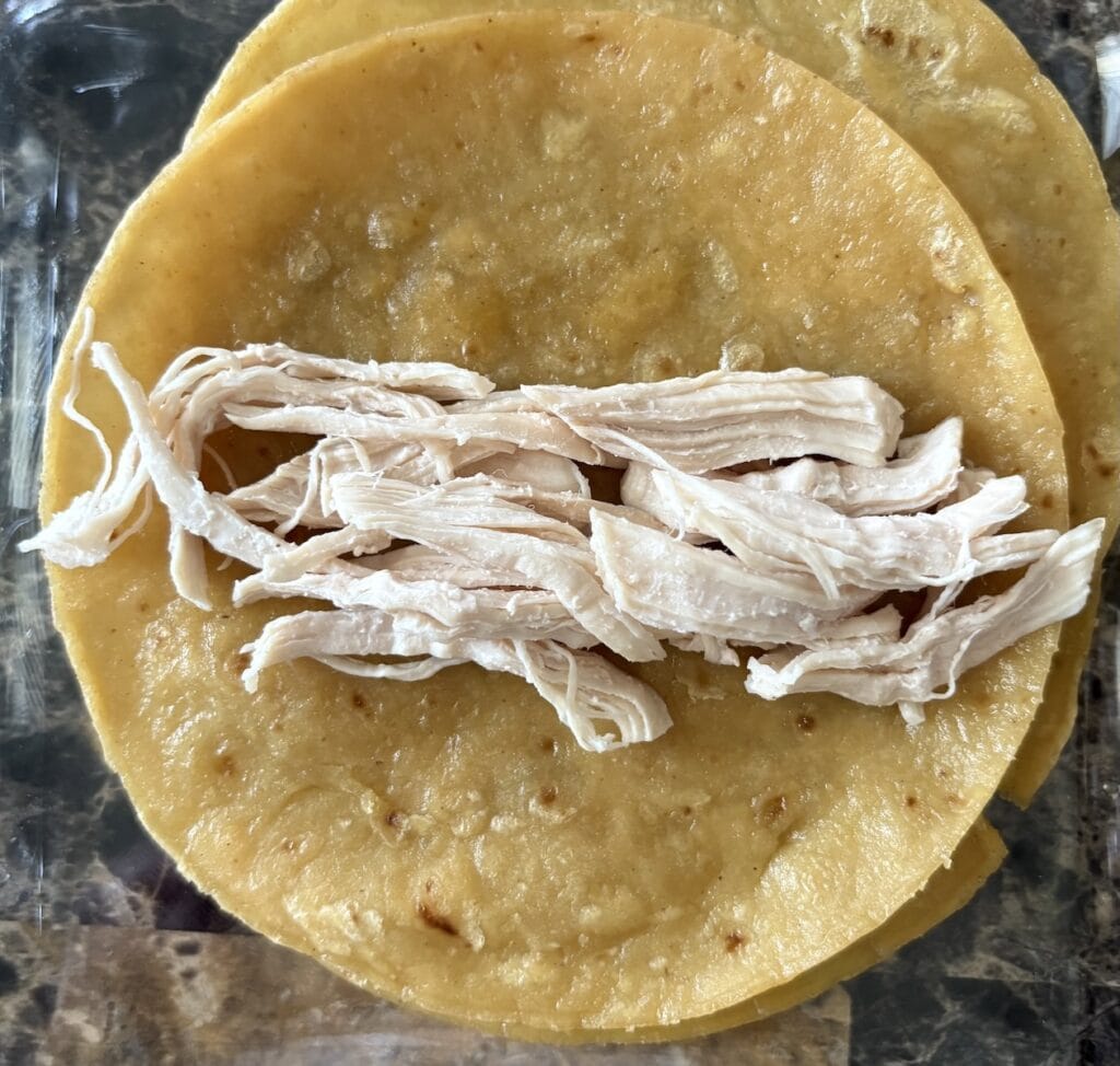 Top view of tortilla topped witch shredded chicken.