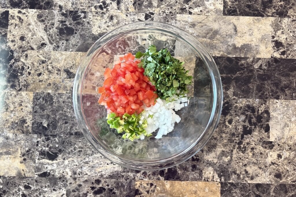 Top view of pico de gallo finely chopped ingredients in a glass bowl.