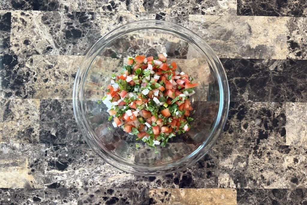 Top view of pico de gallo salsa in a glass bowl.