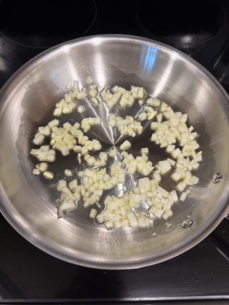 Top view of sauteed chopped white onion in a skillet.