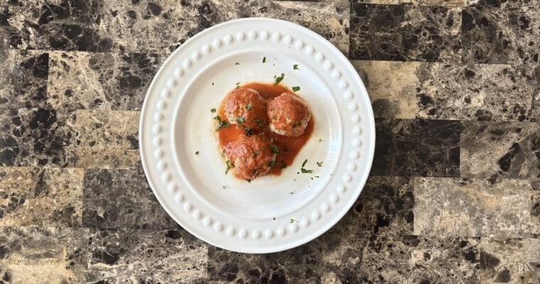 Top view of chipotle meatballs on a plate garnished with chopped parsley.