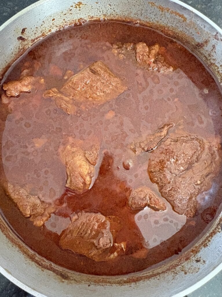 Top view of birria beef chuck roast after it has been cooked in a pot.