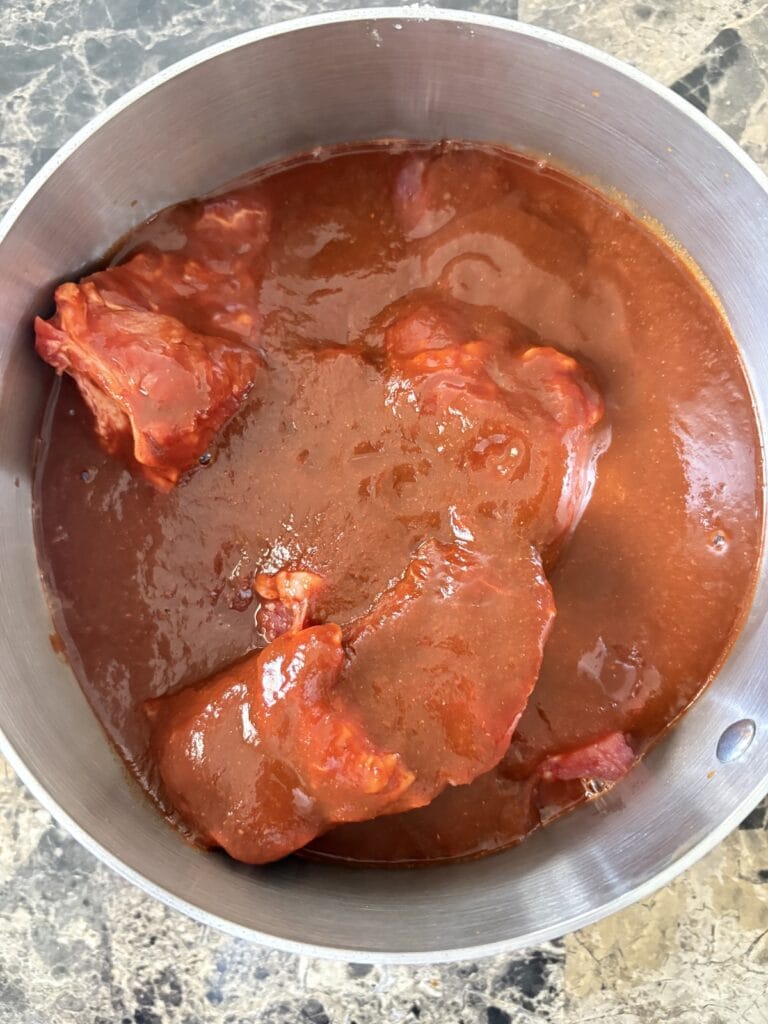 Top view of beef chuck roast in a pot covered in birria marinade.